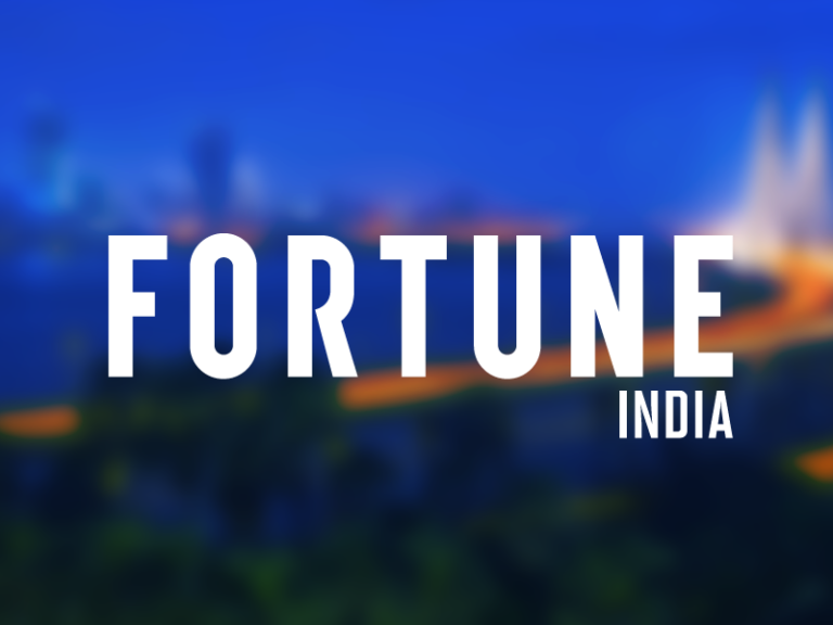 fortune india logo over a blurred photo of india skyline at dawn