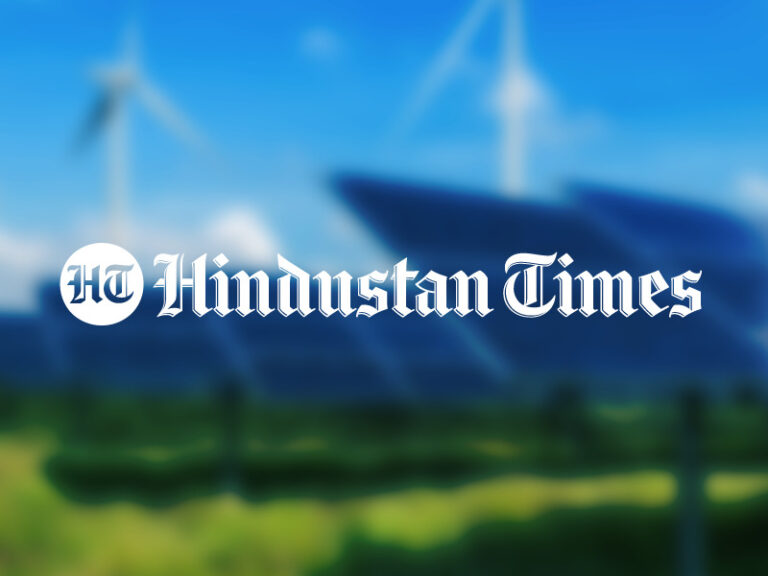 Hindustan Times logo over a blurred photo of solar panels and wind turbines