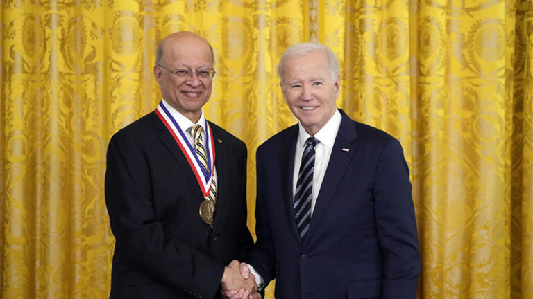 A photo of Ashok and President Biden shaking hands. Ashok has a presidential medal around his neck